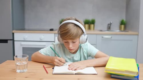 Boy Writing in a Notebook at Home