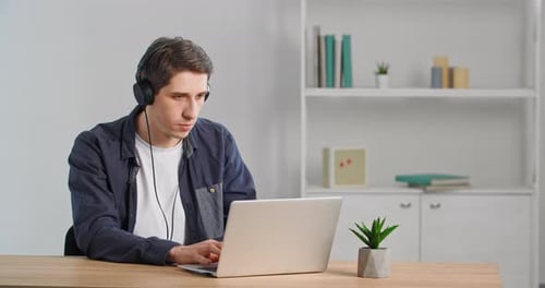 Young Adult Working on Laptop with Headphones Indoors
