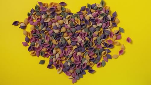 Colorful Pasta Shells Spread on Yellow Background