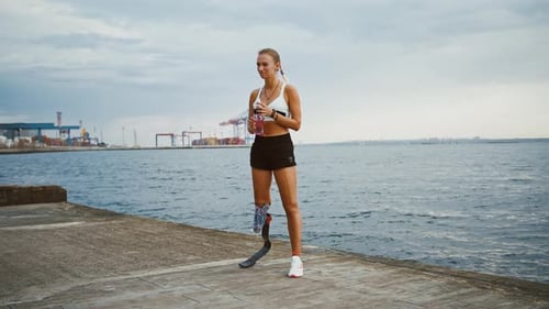 Young Disabled Woman Drinking Water After Training Standing on Pier Near Sea Slow Motion