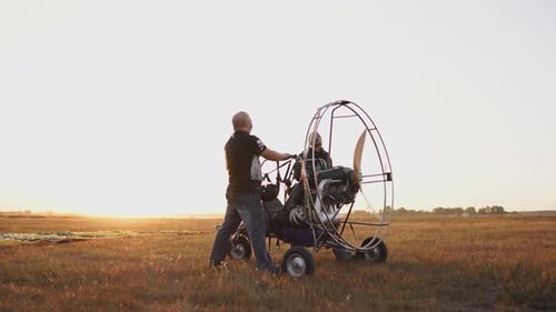 Der Motorparaglider steht bei Sonnenuntergang mit einem Holzpropeller auf dem Feld