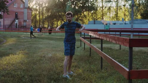 Young Man Stretching Outdoors on Grassy Field