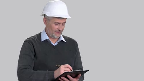 Mature Adult Wearing Hard Hat Taking Notes