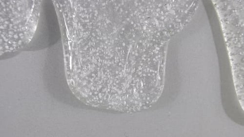 Transparent Cosmetic Gel Fluid Flowing Down on a White Surface