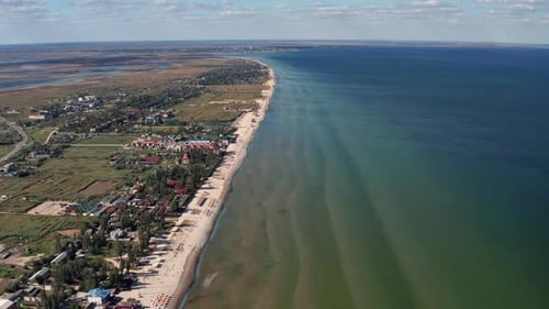 Beautiful flight in summer over the beach. People are resting near the sea. Houses for tourists.