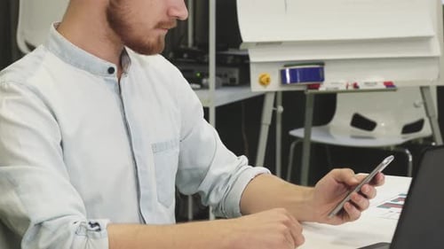Man Using Laptop and Smartphone at Office Desk
