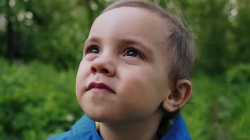 Portrait of Adorable Baby Boy Smiling and Laughing on Green Forest Background. Cute Kid in Blue
