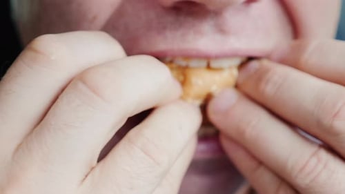 A Hungry Man Eagerly Eats a Hamburger Only His Mouth is Visible in the Frame