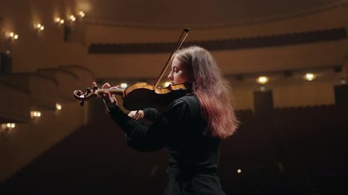 Woman Plays Violin on Stage in Empty Venue