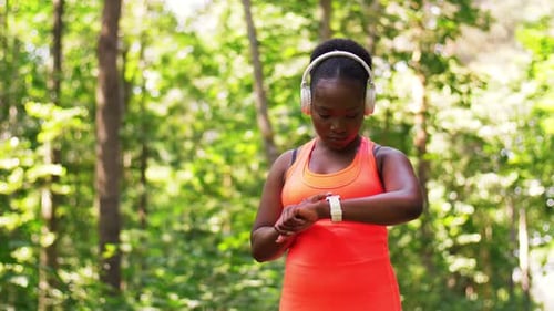Woman Pauses to Check Smartwatch in Forest