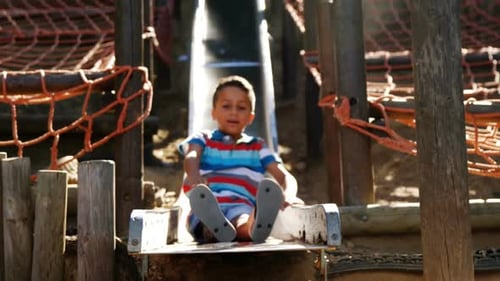 Schoolboy sliding on slide in school playground