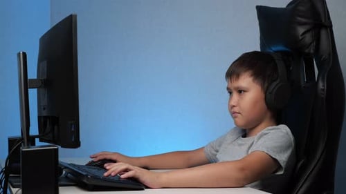 Junge mit Kopfhörern spielt am Computer