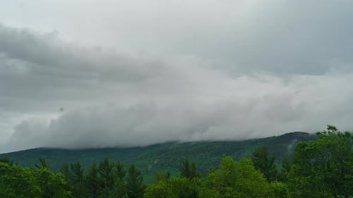 Fog and clouds rolling over lush forest and mountains during dusk time lapse (4k)