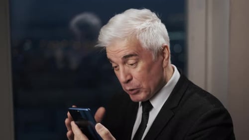 Senior Man in Suit Using Mobile Phone at Night