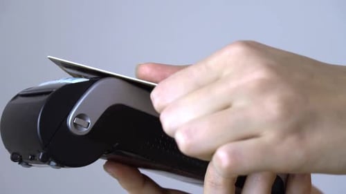 a woman's hand brings a plastic card to the terminal and pays contactless