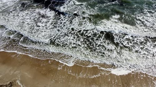 Flug mit Drohnenansicht über Meereswellen, die auf Sandy Shore rollen