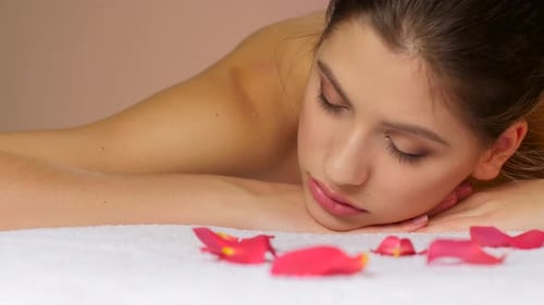 Relaxing Woman Lying on Massage Table with Flowers