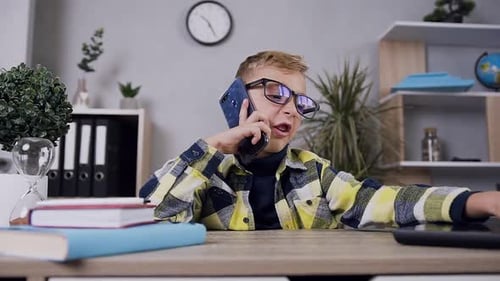 Child Using Laptop and Talking on Phone Indoors