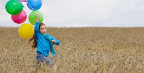 Girl Runs Through Wheat Field Holding Balloons