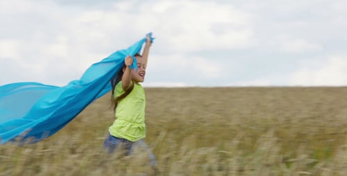 Girl Runs Through Wheat Field with Blue Fabric