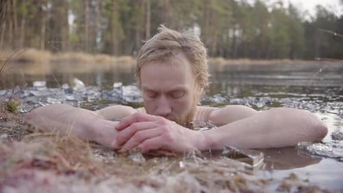 Un baigneur de glace se concentre sur la respiration consciente alors qu'il est assis dans un lac gelé