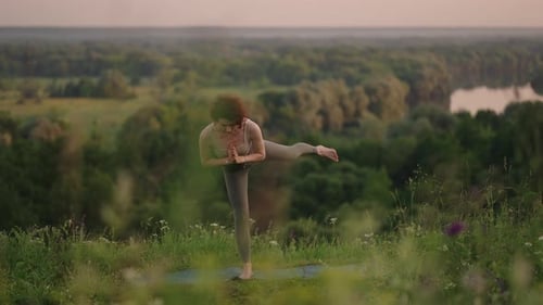 Woman Practices Yoga on Grassy Hill at Sunset