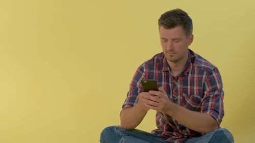 Man Using Smartphone while Sitting Cross-Legged Indoors