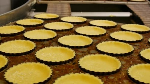 Dough with sugar at the conveyor belt of a bakery factory