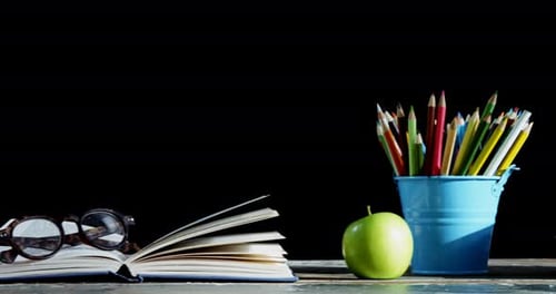 Green apple and school supplies on table