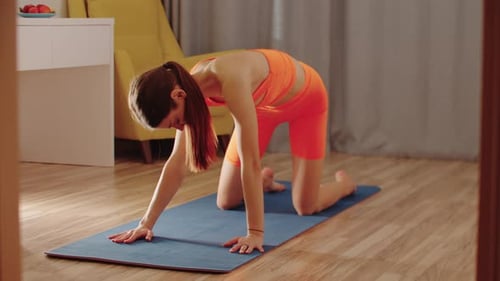 Young Woman Stretches on Yoga Mat at Home