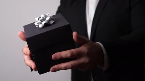 Man Holds Black Gift Box with Silver Bow