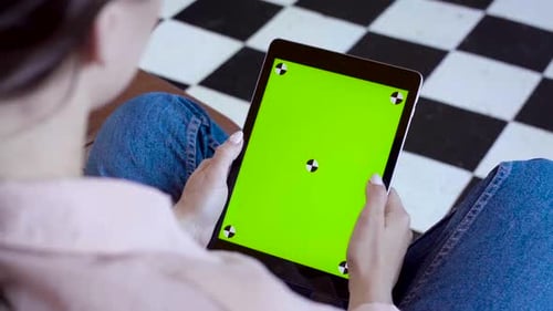 Close-up of woman holding tablet and touching green screen