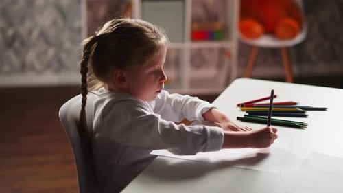 Mädchen zeichnet Illustration auf Papier und sitzt im Kinderzimmer