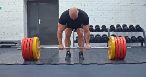Man Lifting Heavy Barbell in Gym