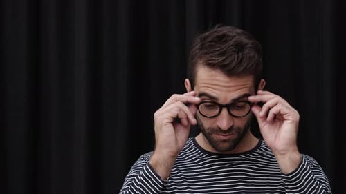 Confident Man Poses, Removes Glasses in Studio