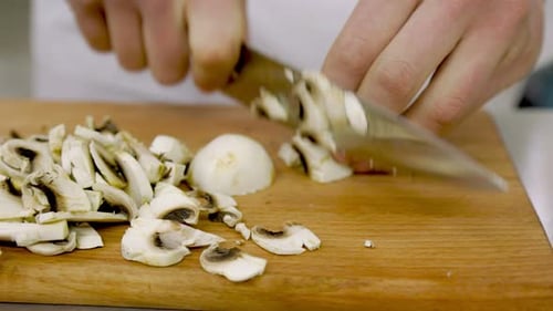 Chef cutting fresh mushrooms on cutting board