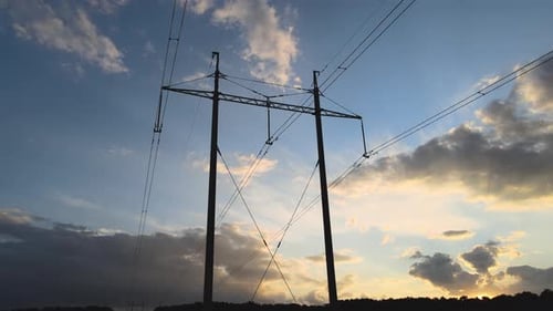 Dark Silhouette of High Voltage Tower with Electric Power Lines at Sunset