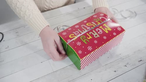 Woman Wraps Christmas Present with Silver Ribbon