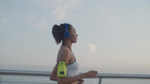Female Runner in Headphones Jogging at Sunrise