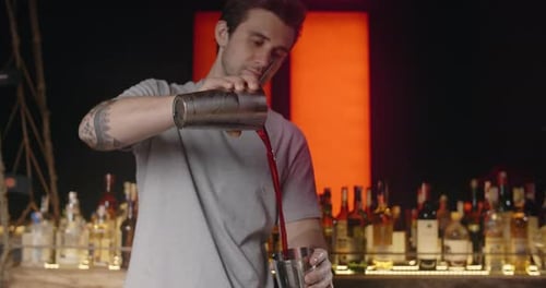 Bartender Mixing Cocktail at Night in Dark Bar