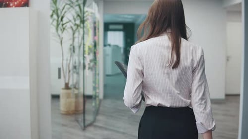 Young Attractive Woman Walks Around the Office with a Folder for Papers