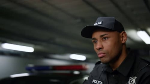 Police Officer Holds Gun Near Flashing Police Car