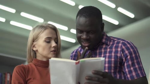 European Lady and African American Man Discuss Book in the Library