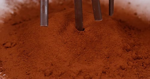 Chocolate Sticks Falling Into Cocoa Powder in Close Up