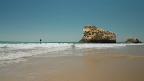 A Young Man Surfer Floats on Paddleboard on the Tropical Sea Into the Far Away