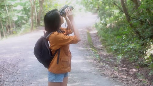 Woman with Binoculars Exploring Forest Path
