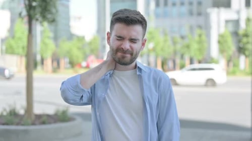Young Man Experiencing Neck Pain on City Street