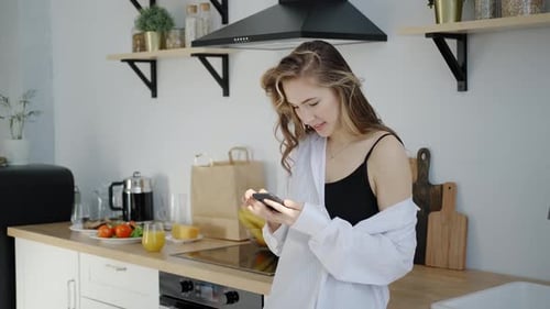 Young Woman Using Smartphone in Modern Kitchen