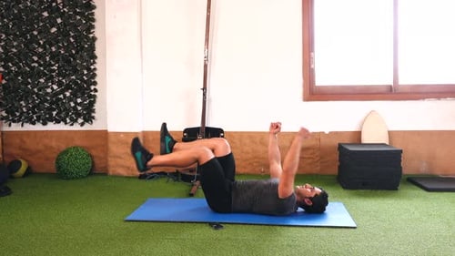 Variation der Bauchmuskelübungen mit Muskeltrainer auf blauer Matte