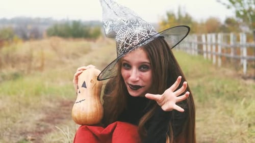 Happy Person in Witch Costume Holding Pumpkin